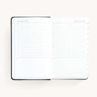 2025 Daily Dapperdesk Planner by Emily Ley in the Black Tie leatherette cover open to a two-page daily spread featuring Sunday and Monday. Features a clean, minimalistic design with lined sections for daily tasks, to-do lists, and notes.