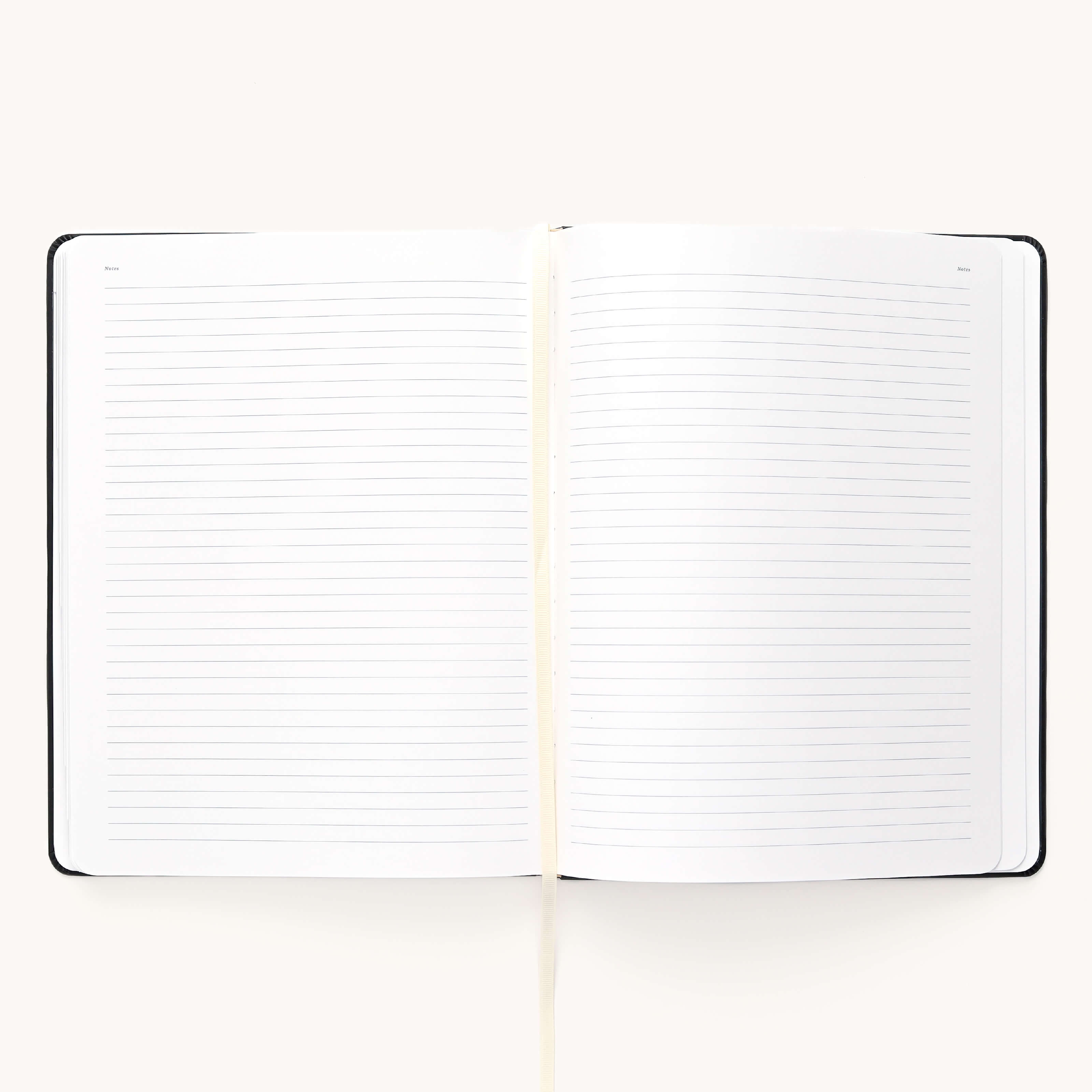 A 2024-2025 Weekly Dapperdesk Planner by Simplified, featuring high-quality paper and a cream-colored ribbon bookmark, flaunts its black leatherette cover against a light backdrop.