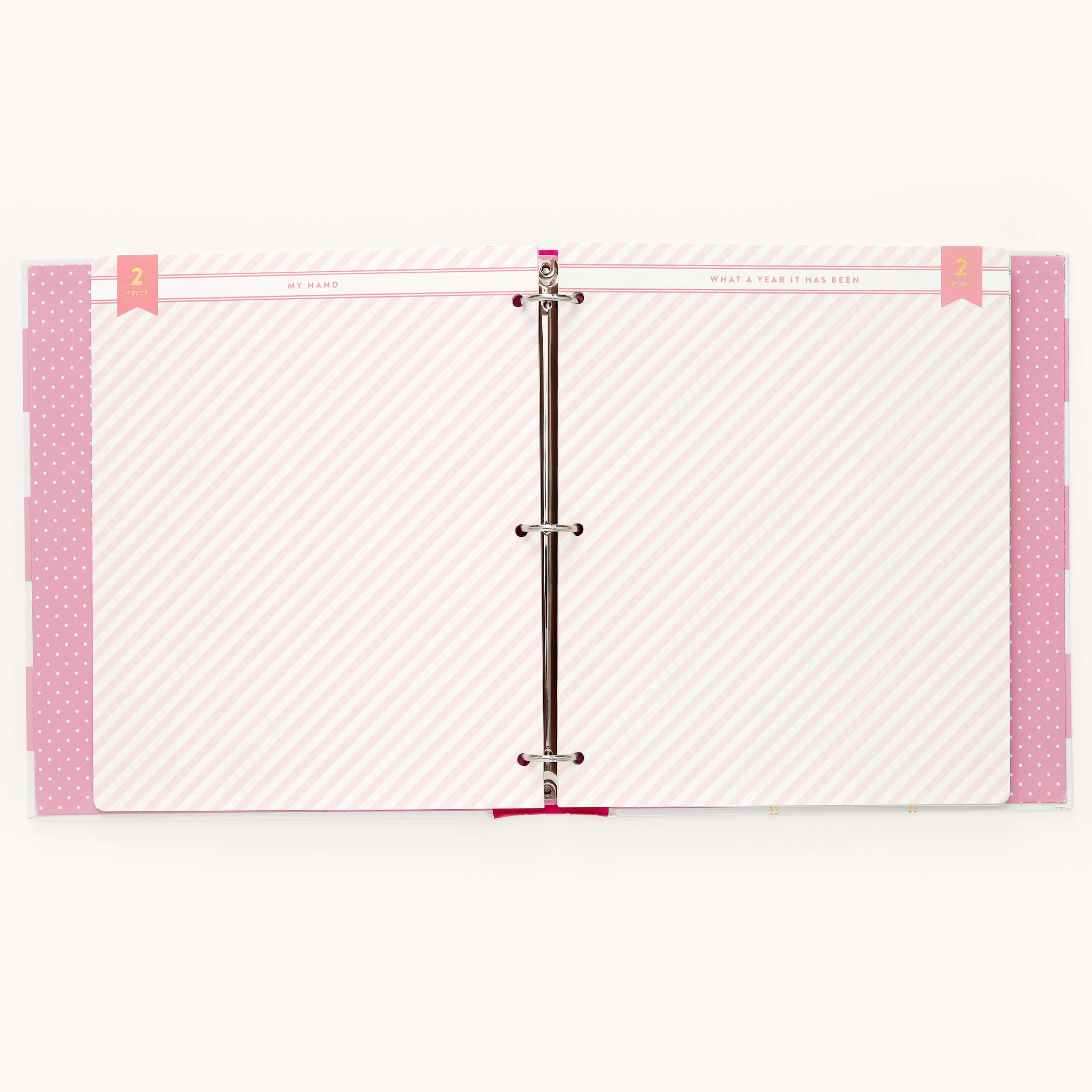 Open the Raspberry Big Kid Book by Simplified, featuring vibrant pink and white diagonal striped pages with pink polka-dotted tabs on the left. A pink banner with Simplified and What a Year It Has Been completes this colorful binder capturing a childs adventures.