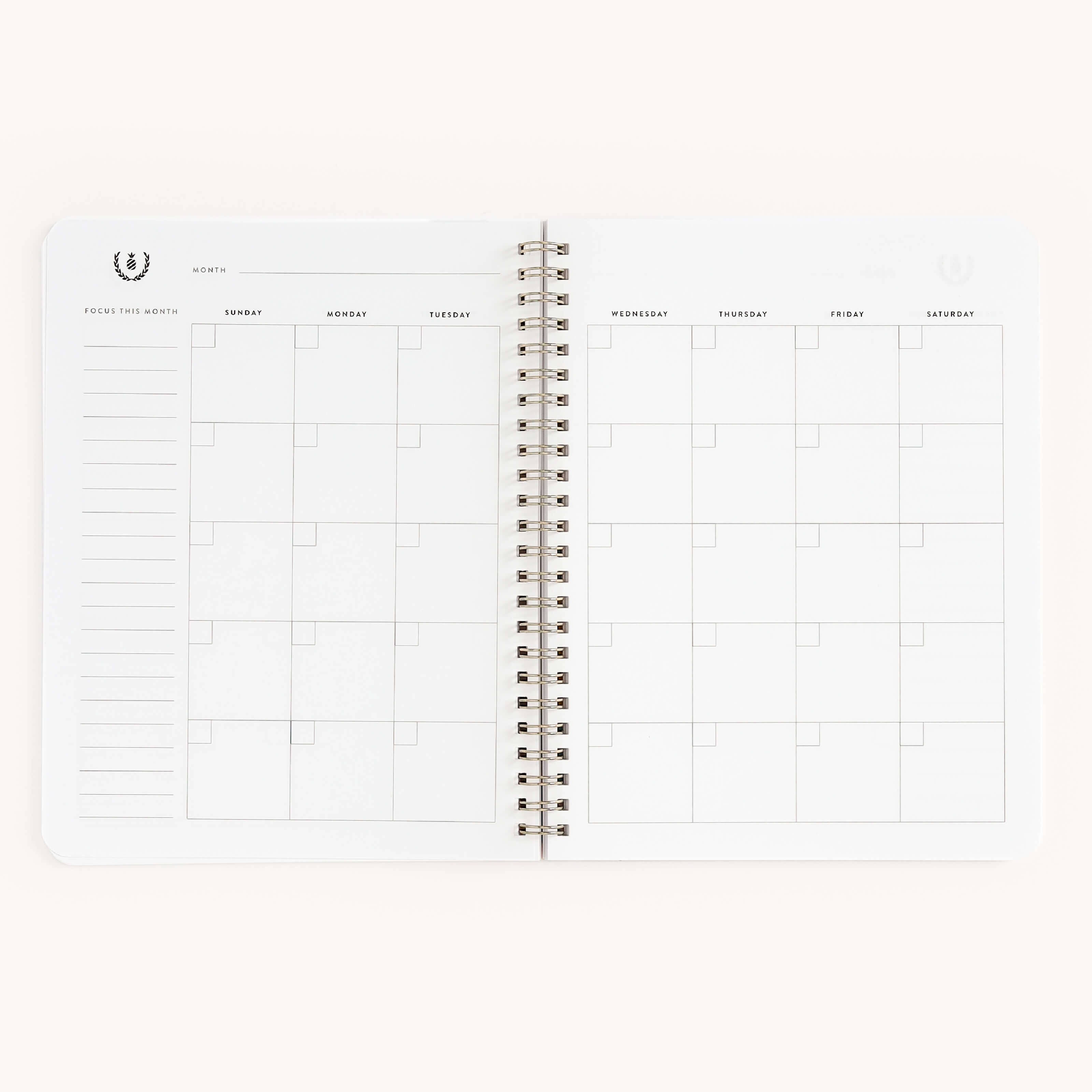 The Workbook - Meal Planning by Simplified is a spiral-bound planner featuring a minimalist monthly calendar with space for notes and meal planning. Days start with Sunday on the left, making it perfect for organizing grocery shopping.