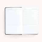 2025 Daily Dapperdesk Planner by Emily Ley in the Black Tie leatherette cover open to a two-page daily spread featuring Tuesday and Wednesday. Features a clean, minimalistic design with lined sections for daily tasks, to-do lists, and notes.