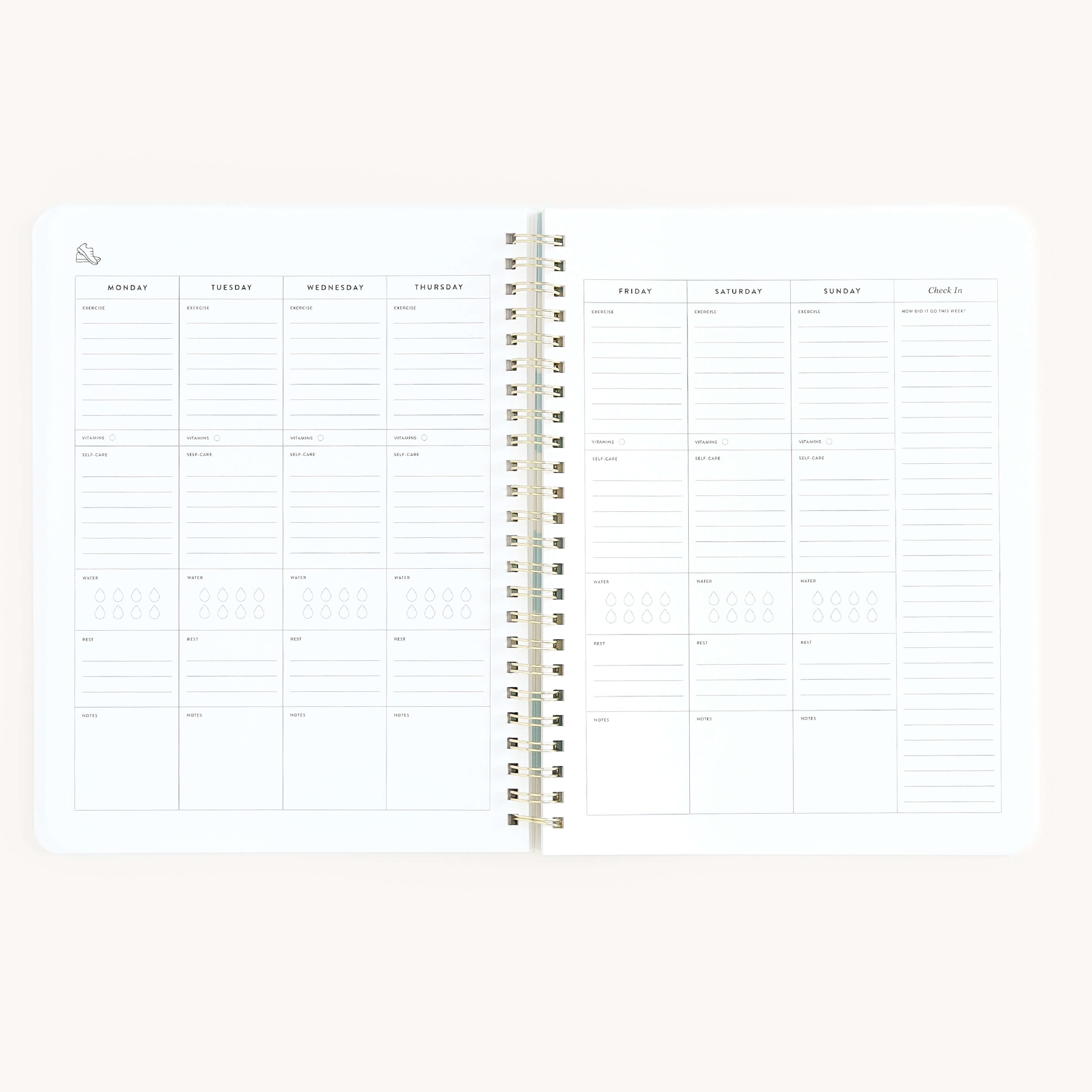 The Workbook - Wellness by Simplified is an open spiral-bound planner on a light background, with a weekly layout for goal tracking. Each day is labeled at the top with spaces for notes or tasks, and the lower section includes areas for checklists or self-care entries.