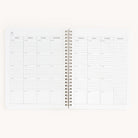 The Simplified Workbook - Meal Planning is a spiral-bound planner with a minimalist weekly layout from Sunday to Saturday. It features time slots from 6 AM to 7 PM, except reduced slots on Sunday, plus a Grocery List section for organized shopping.