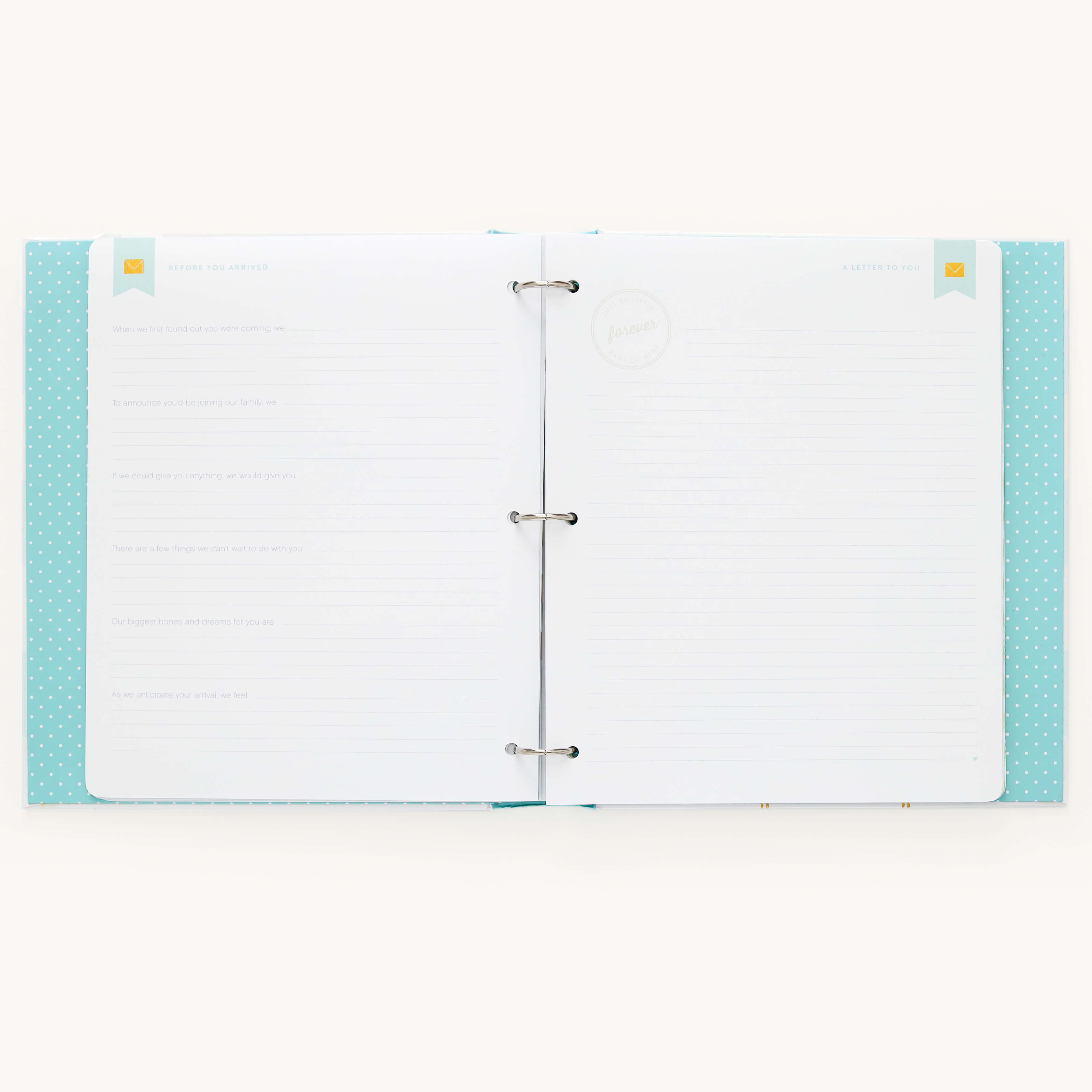 An open Simplified Baby Book - Mint binder with a light blue cover and polka dot pattern is shown. Inside, customizable page packs offer guided writing space with faint lines and decorative banners. Its perfect for crafting a personalized baby book on any flat surface.