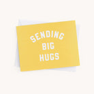 From the Simplified Boxed Card Set, a yellow card with SENDING BIG HUGS in bold white text is paired with a plain white envelope, ideal for any occasion against a light background.