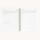 The Simplified open spiral-bound planner includes Simplified Ideas and the Workbook - Meal Planning, with the left page for routine and holiday ideas, and the right page for organizing breakfast, lunch, dinner, and snacks to simplify grocery shopping.