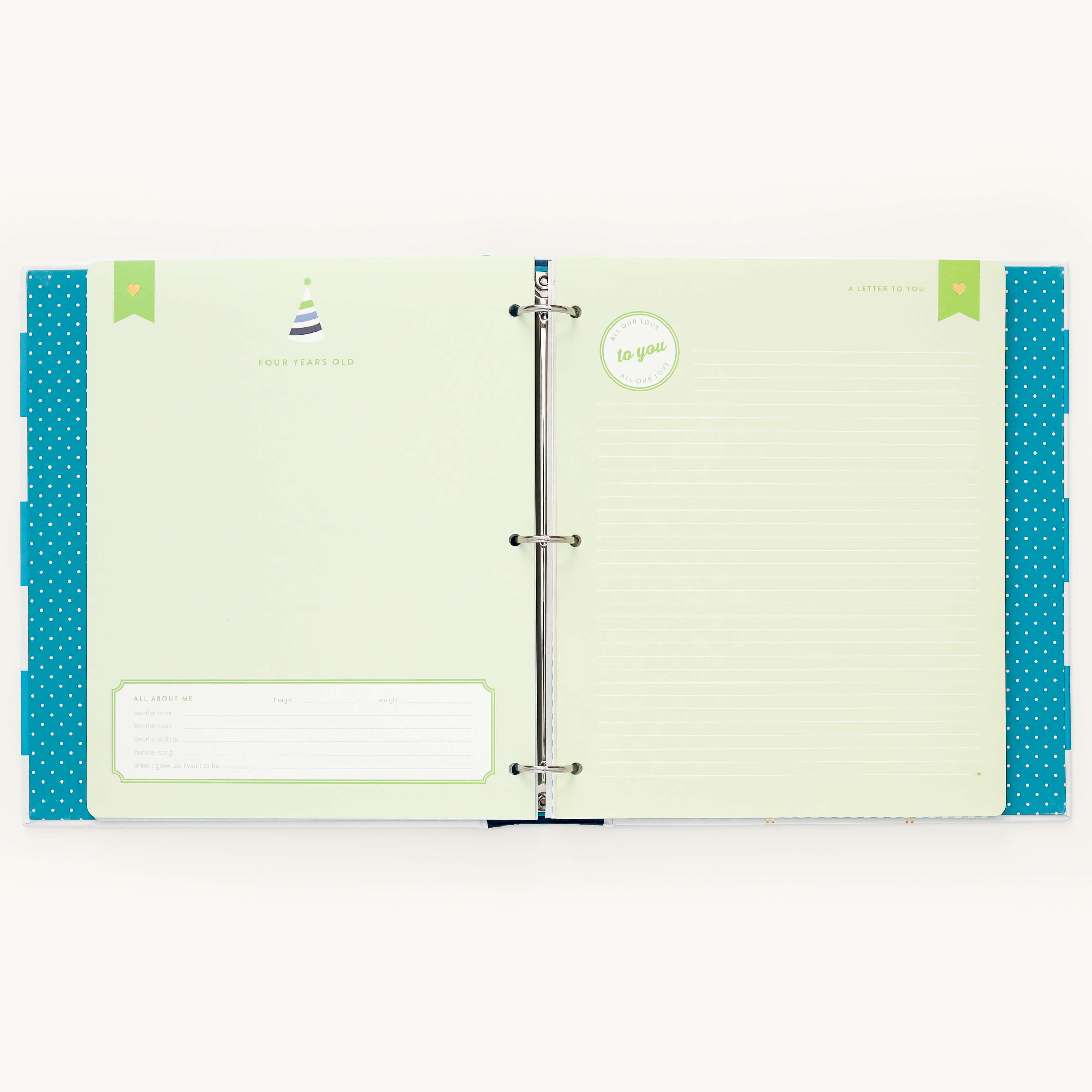 An open binder reveals two pages: the left, inspired by Simplifieds Teal Big Kid Book, displays a birthday hat icon and personal info sections for tracking child growth. The right page, framed by green accents and blue polka-dot borders, features to you, ruled lines for writing, and a circular design.