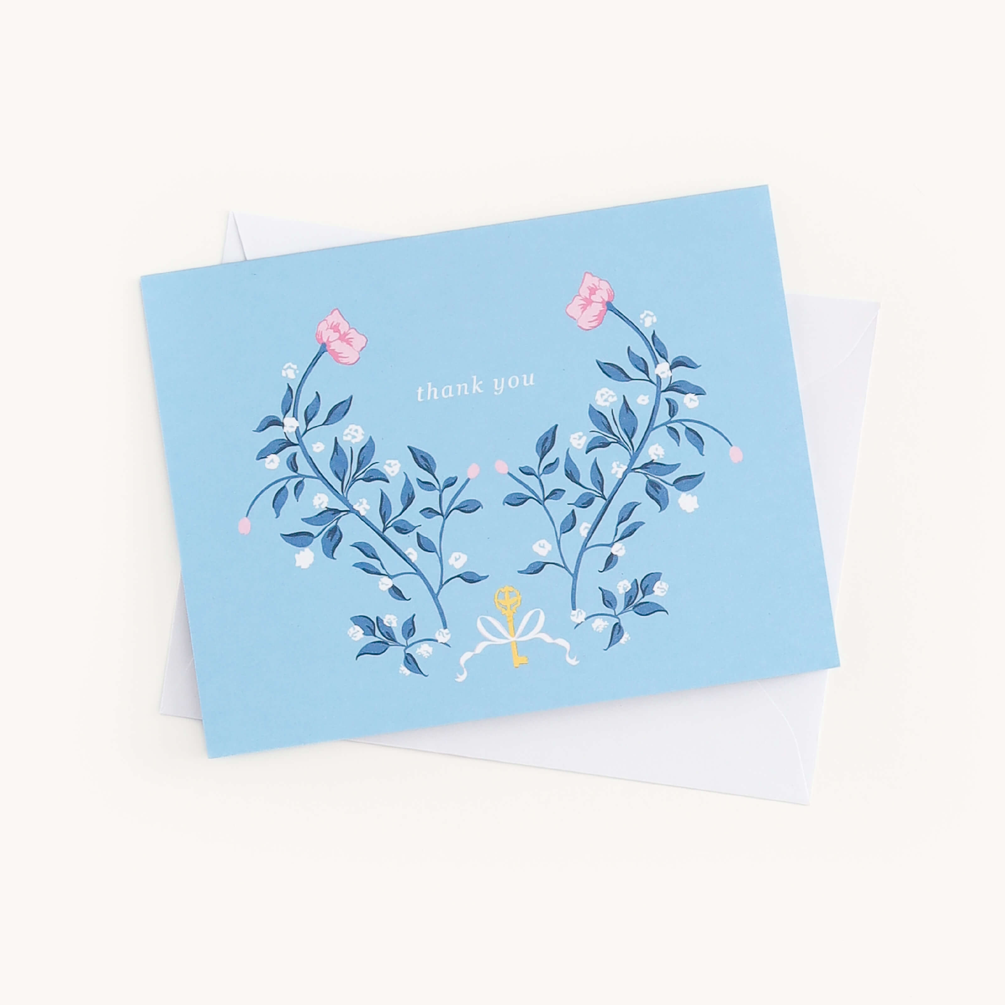 A Simplified Boxed Card Set includes a blue thank you card with elegant floral designs of pink and yellow flowers, green leaves on the front, and an envelope partly visible behind it, perfect for any occasion.