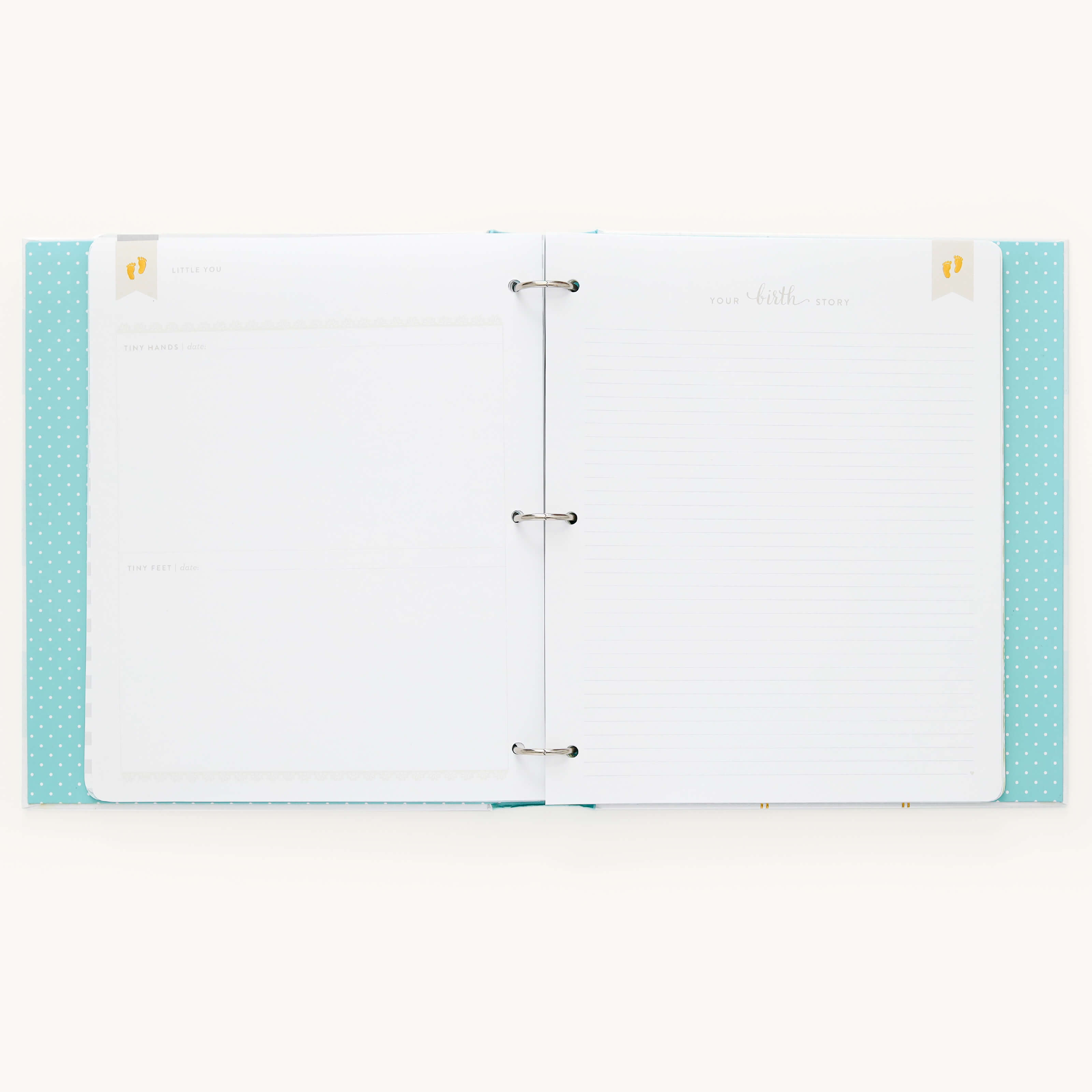 The open Baby Book - Mint by Simplified has a light blue, polka-dotted cover with customizable page packs, guided writing space for birth story details, and minimalist designs. It features metal binder rings to inspire creativity.