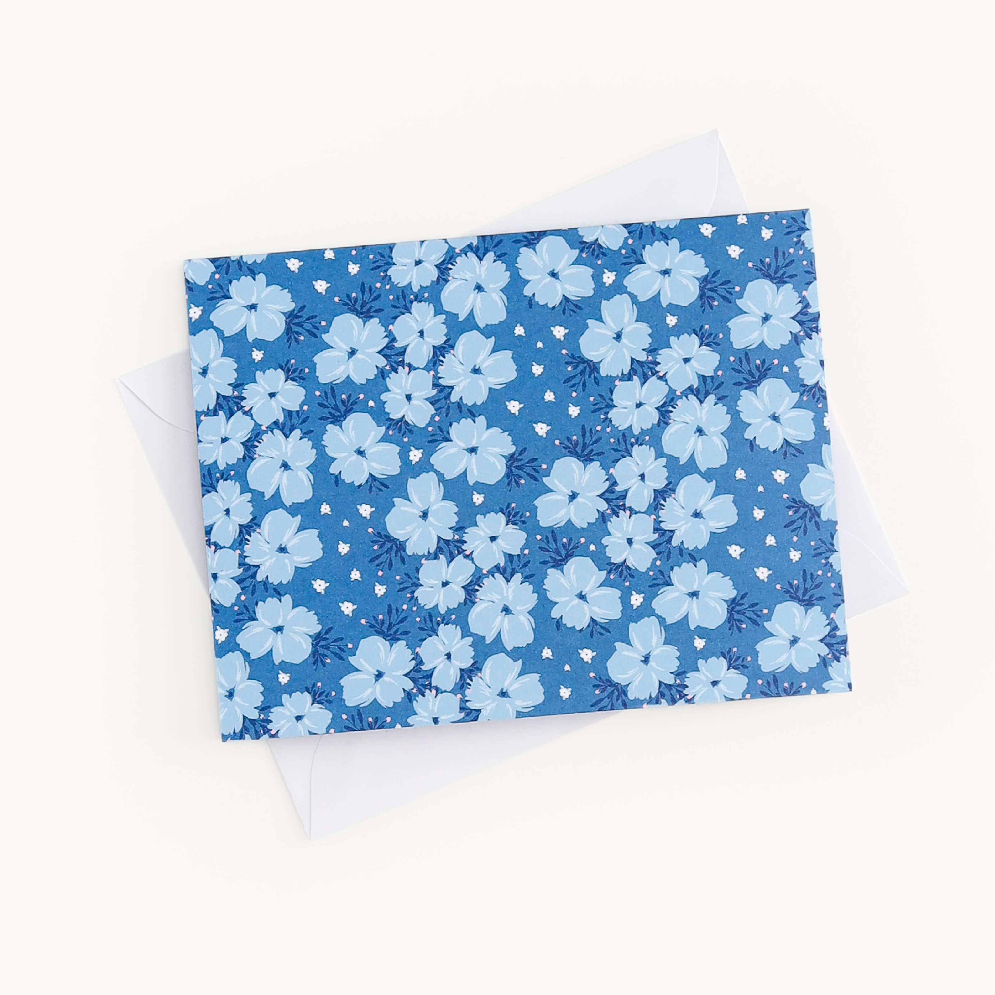 The Simplified Boxed Card Set features a blue greeting card with light blue flower patterns on a plain white envelope, perfect for any occasion, all set against an off-white background.