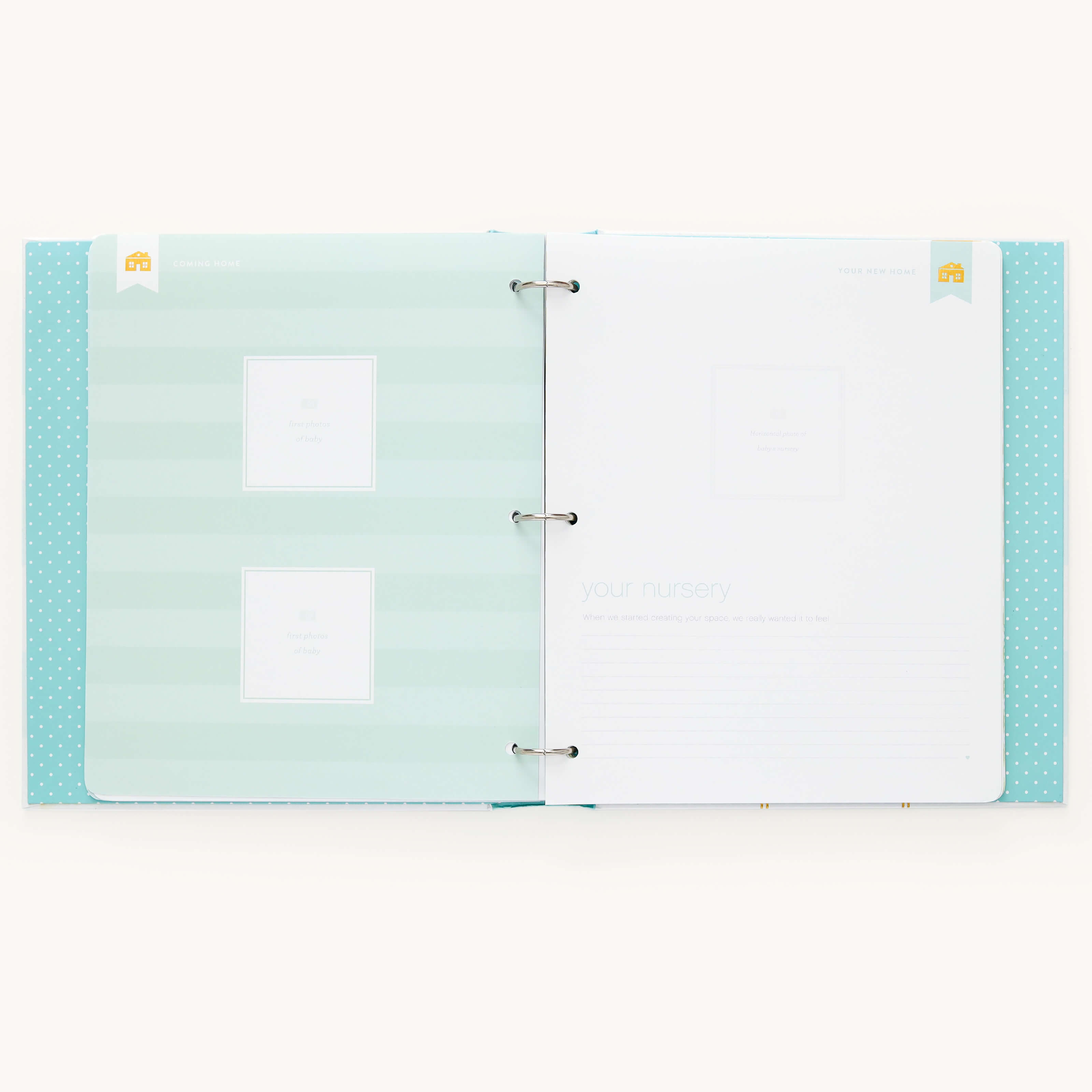 The Baby Book - Mint by Simplified features a two-ring binding with a guided writing space. The left page is light blue with white stripes and two labeled photo slots; the right has your nursery and lines for notes. The polka-dotted cover is blue, and it offers customizable page packs.