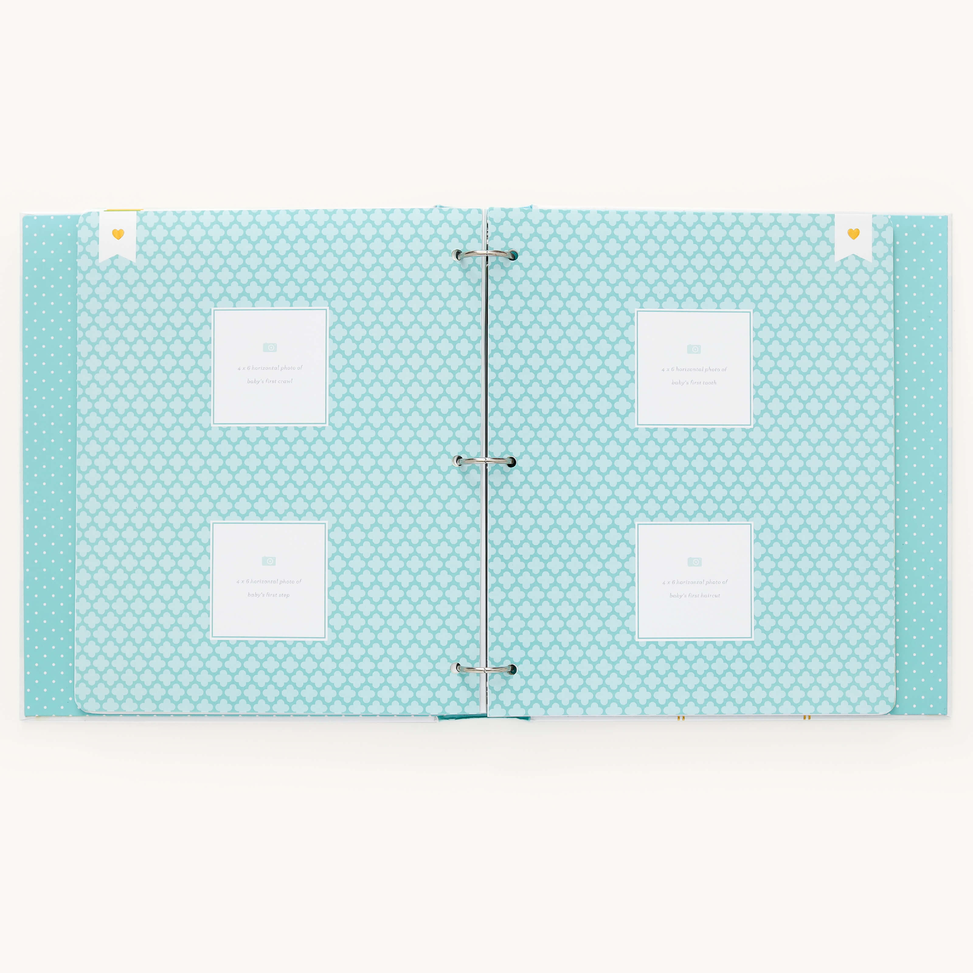 The Simplified Baby Book - Mint features blue patterned pages with four empty photo slots on each side. Metal rings in the center allow for customizable page packs, making it ideal for capturing every precious moment.