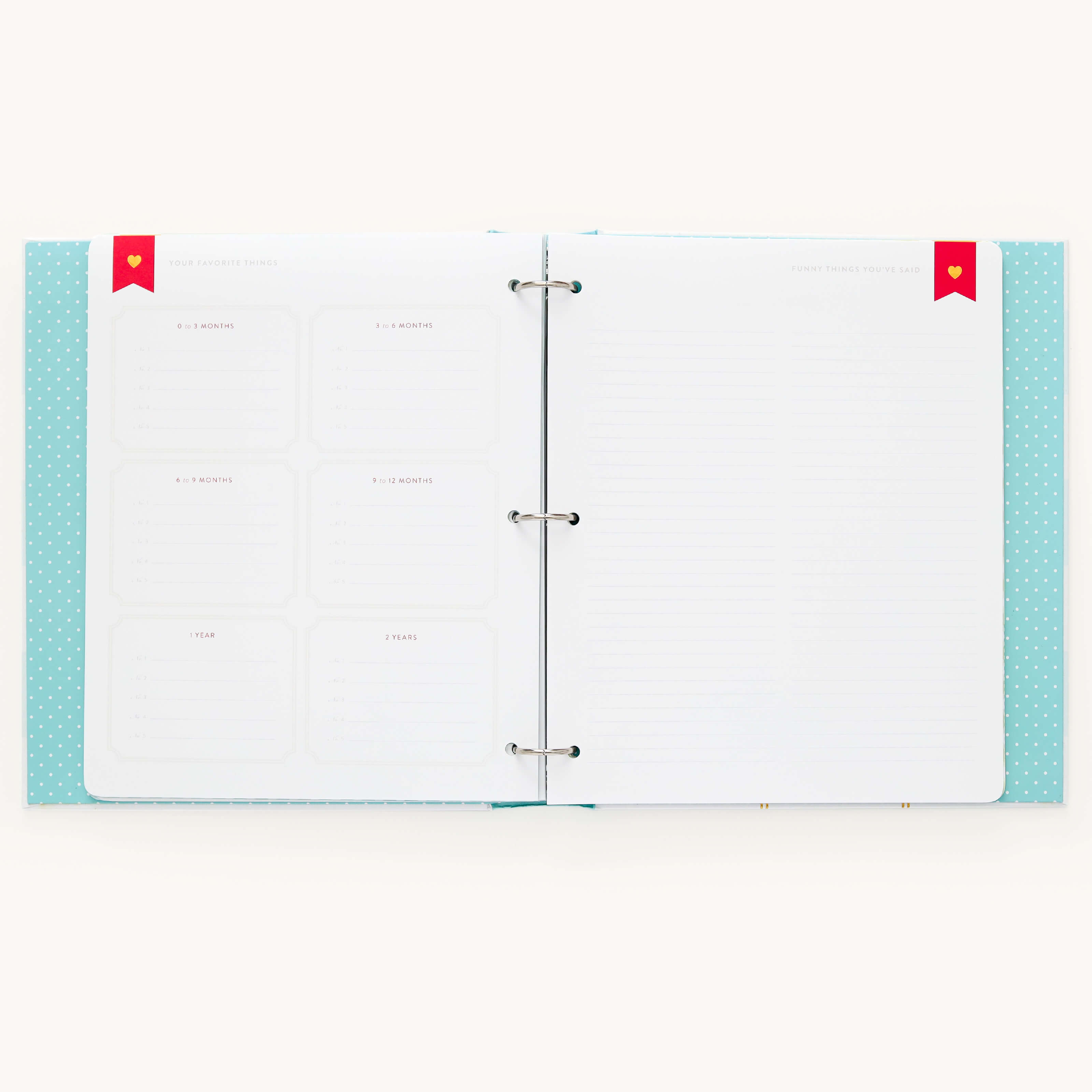 The Baby Book - Mint by Simplified features a turquoise polka dot cover with two-ring binding. The left page has outlined sections for goals like 1 Month and 6 Months, while the right offers guided writing space. It includes red bookmarks on the top corners for enhanced functionality.