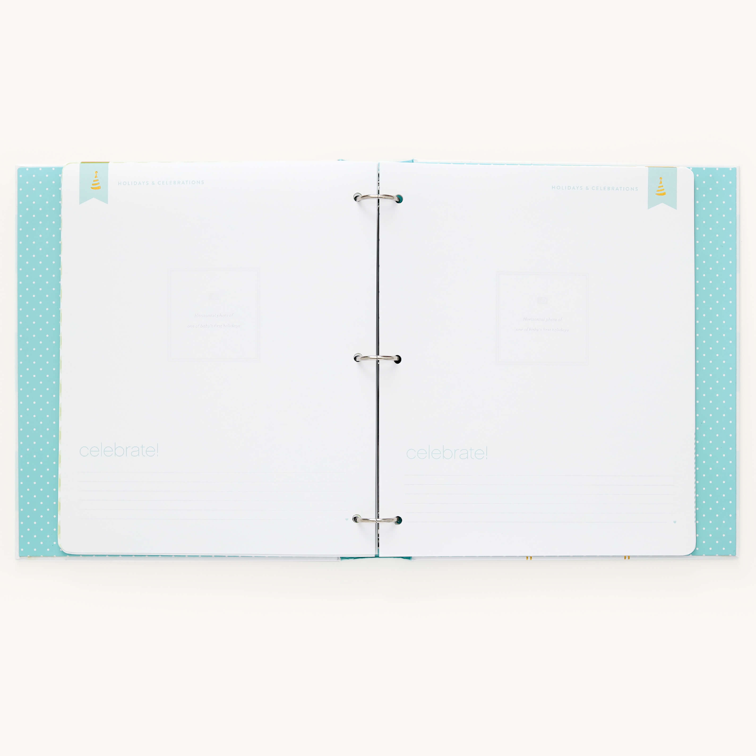 An open scrapbook with blank pages inside a mint, polka-dotted cover. This minimalistic Baby Book - Mint by Simplified features celebrate! at the bottom with silver rings binding the guided writing pages for memories.