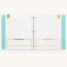 The Baby Book - Mint by Simplified is an open binder with two pages featuring guided writing spaces. The left page has a green section labeled This Keepsake Belongs To while the right page showcases an orange section—this charming feature adds a personal touch to this customizable baby book.