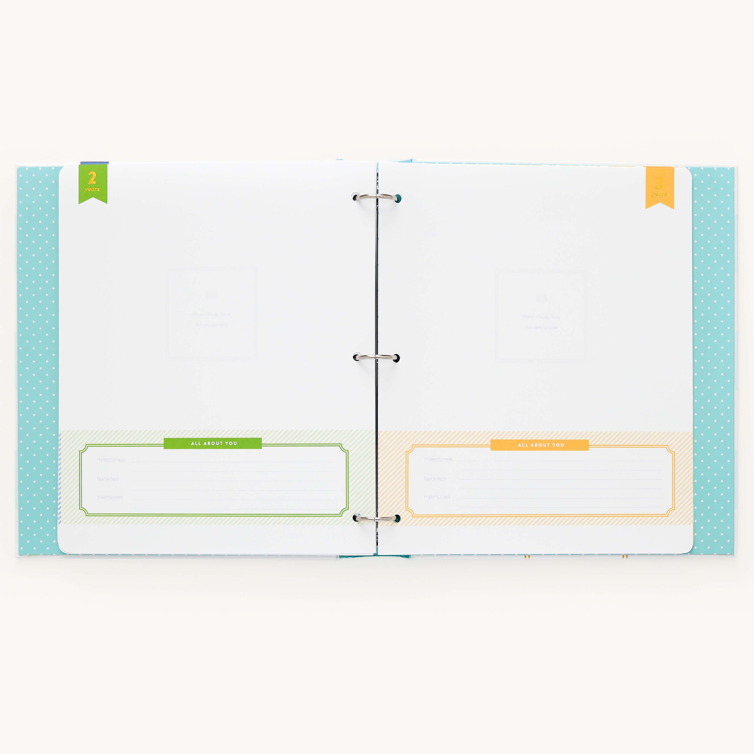 The Baby Book - Mint by Simplified is an open binder with two pages featuring guided writing spaces. The left page has a green section labeled This Keepsake Belongs To while the right page showcases an orange section—this charming feature adds a personal touch to this customizable baby book.