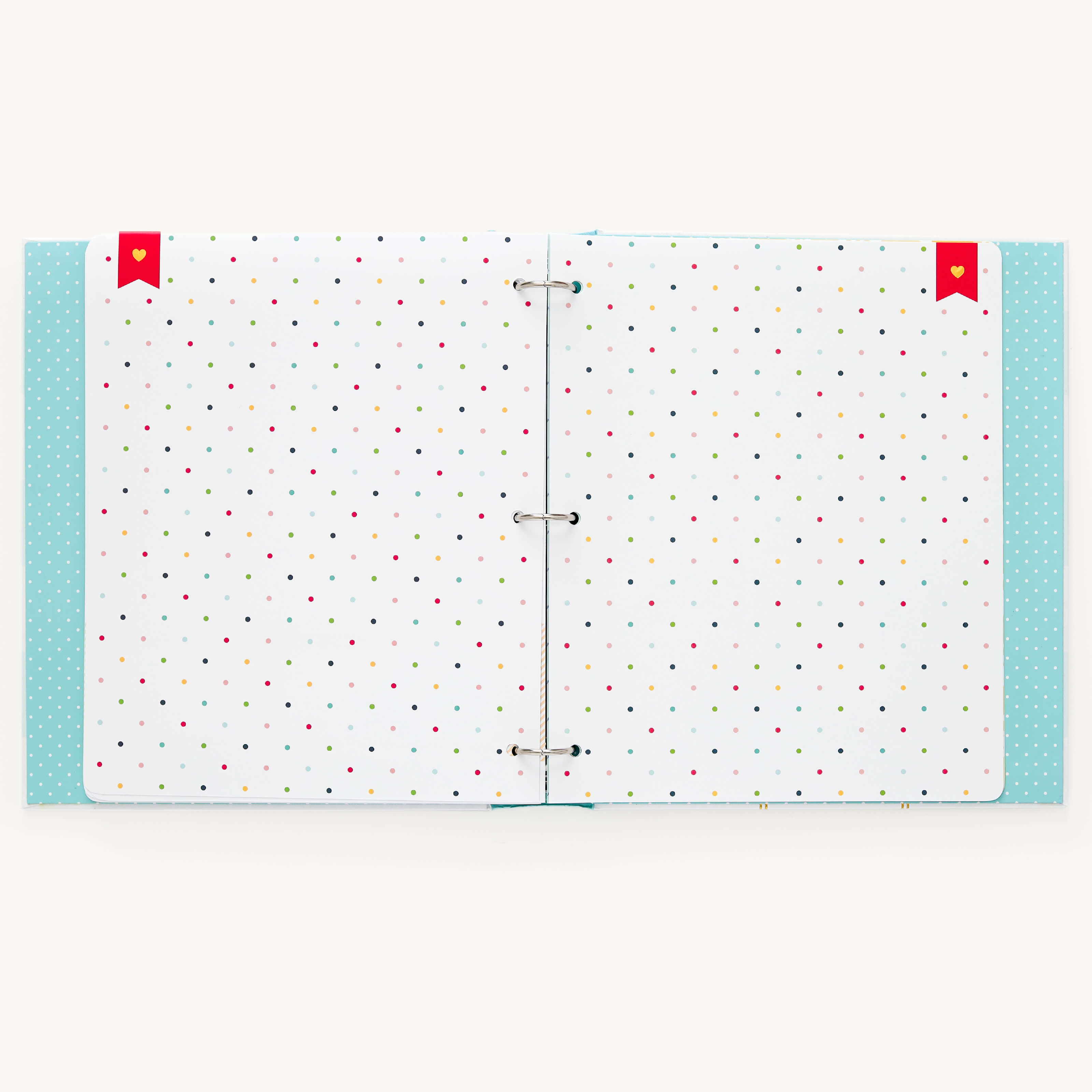 The Baby Book - Mint by Simplified is an open scrapbook with white pages adorned with colorful polka dots and red ribbon bookmarks. The cover edges have a light blue polka dot design. This customizable baby book includes guided writing spaces, ideal for capturing precious memories.