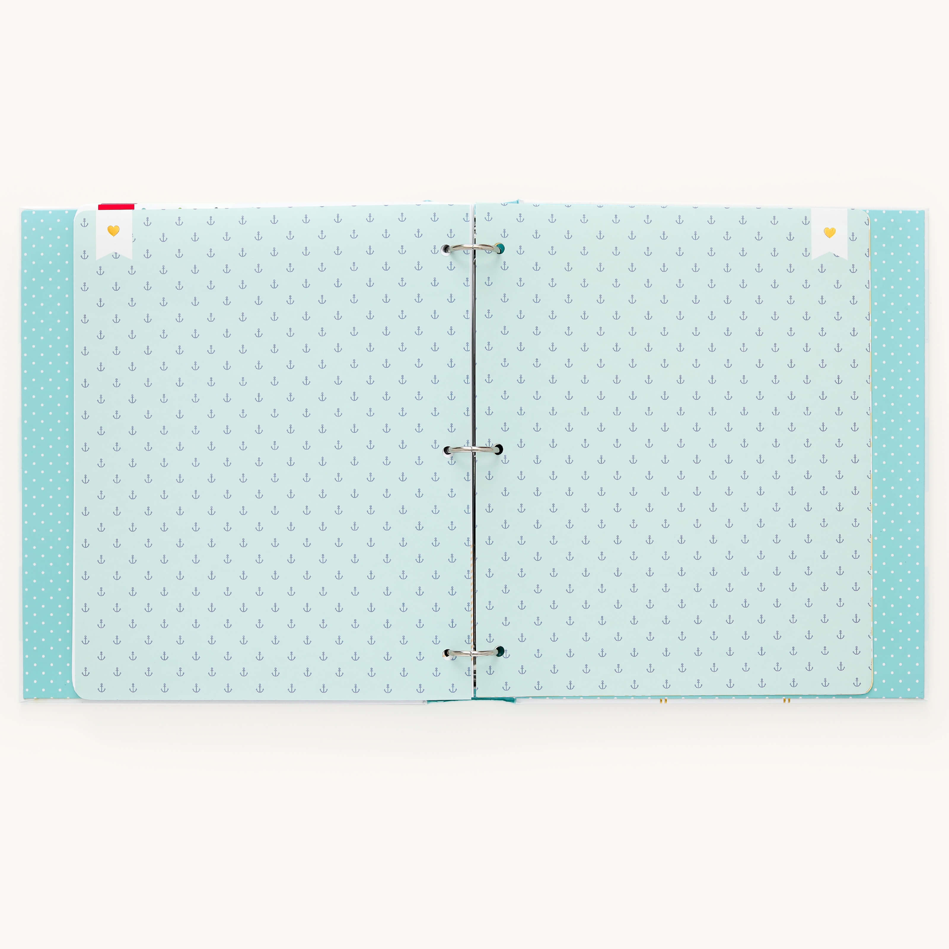 The open Baby Book - Mint by Simplified features light blue pages with small anchor patterns held by visible rings and topped with cute bookmarks. Its plain off-white background creates an ideal guided writing space.