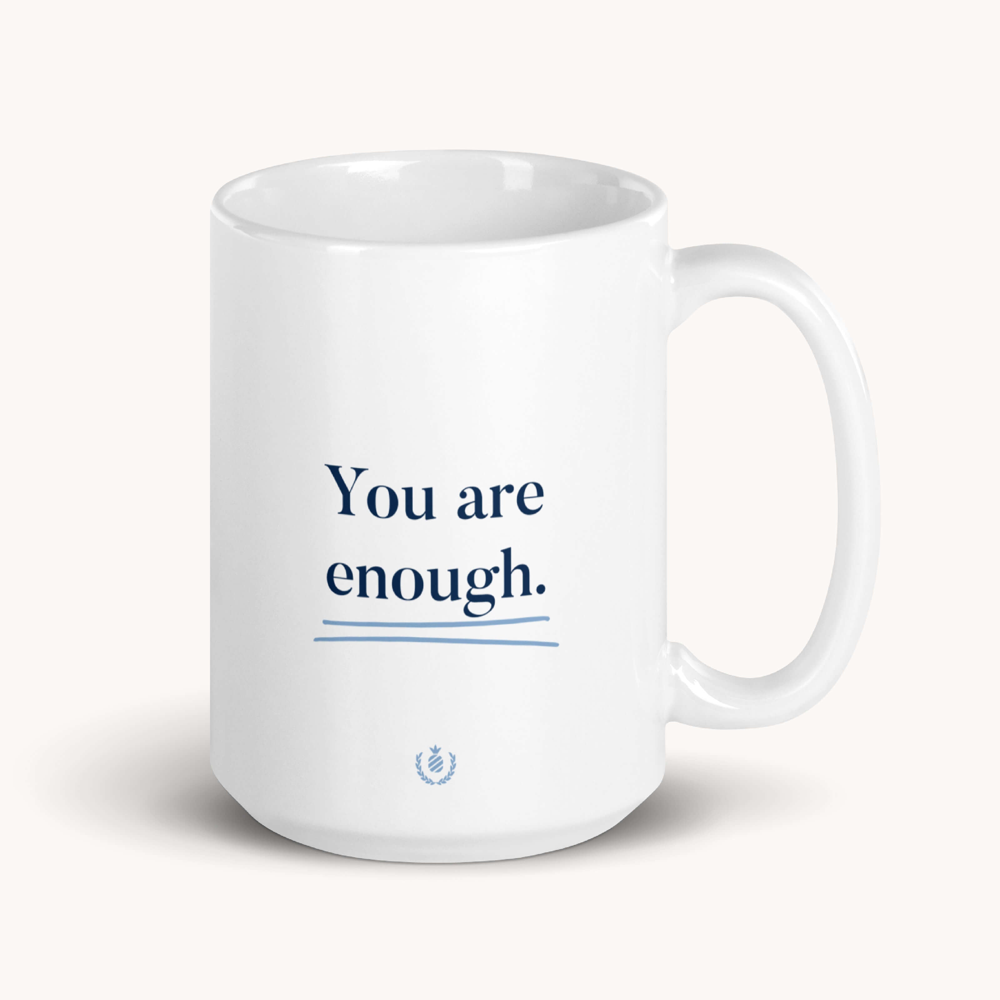 The Mug - You Are Enough by Simplified is a white ceramic mug with an elegant emblem and the uplifting message You are enough in blue text. Its smooth, curved right handle is designed for comfort, making it perfect for enjoying your favorite beverage.