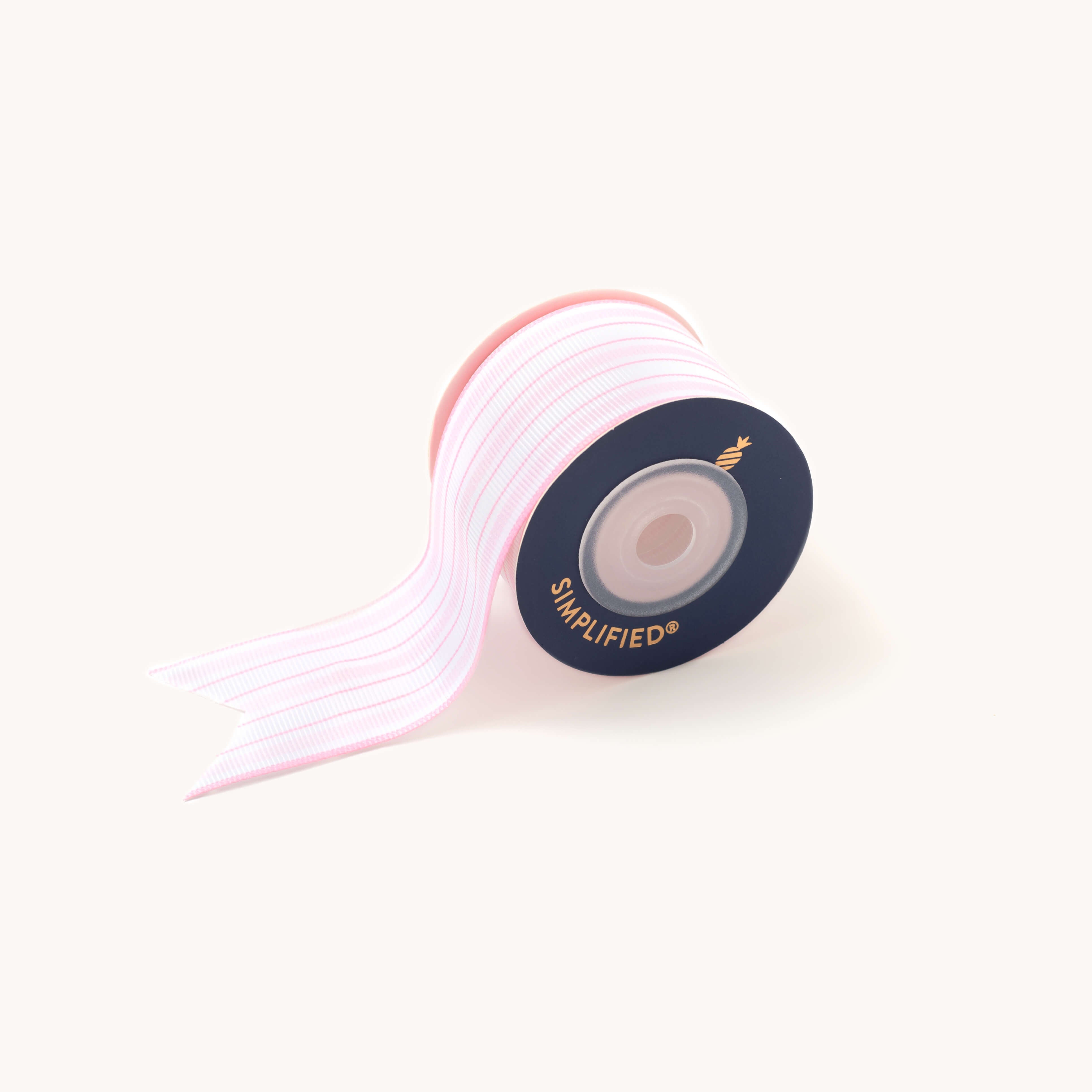 The Blush Stripe ribbon by Simplified, featuring a dark-center spool and white grosgrain with light pink stripes, is shown with a fishtail end on a light background, ideal for elegant gift packaging.