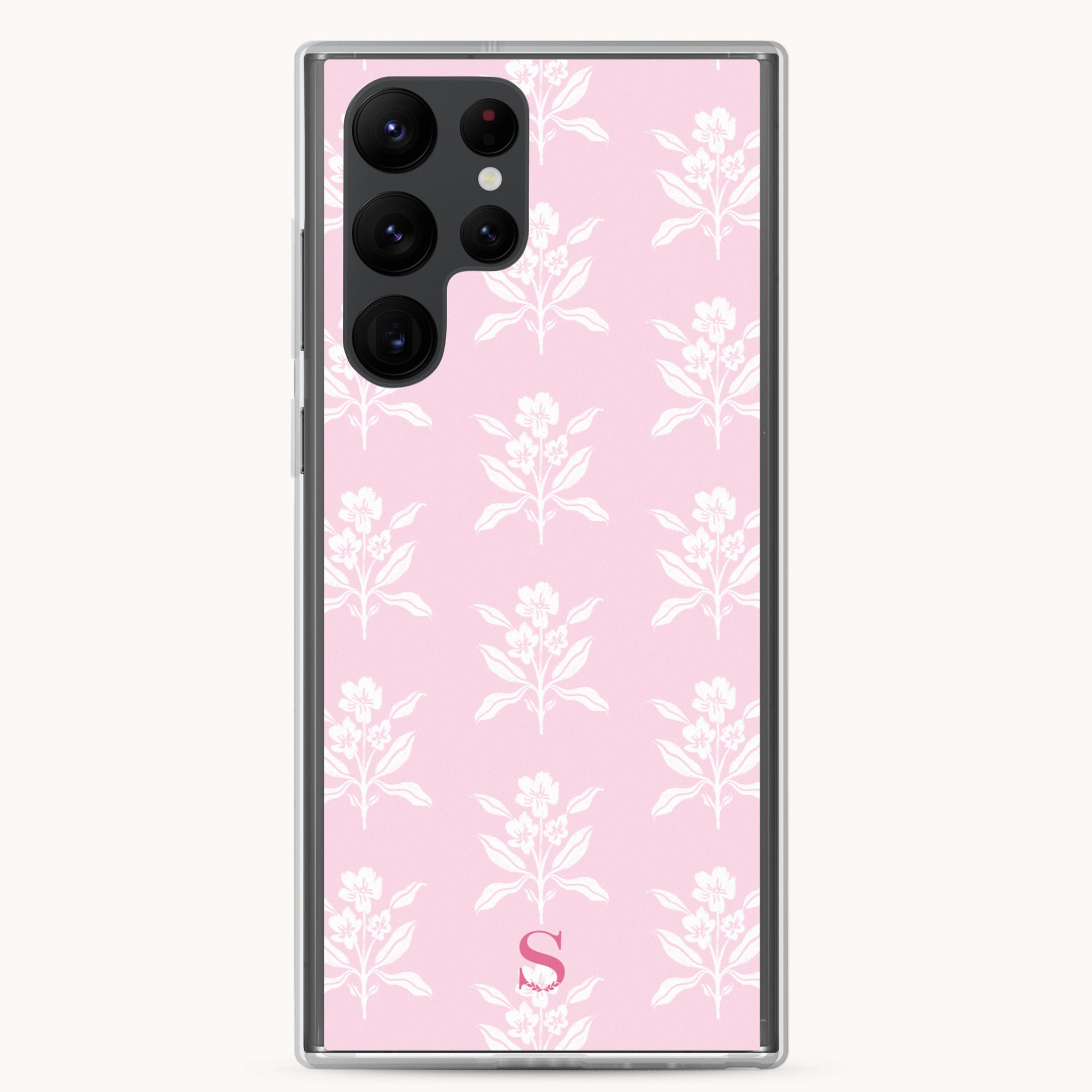 The Samsung Case - Blush Block by Simplified offers a chic design with a pink background and white floral pattern. It features a transparent cover for smartphones, an array of lenses, and a subtle S at the bottom center, combining protection and style.