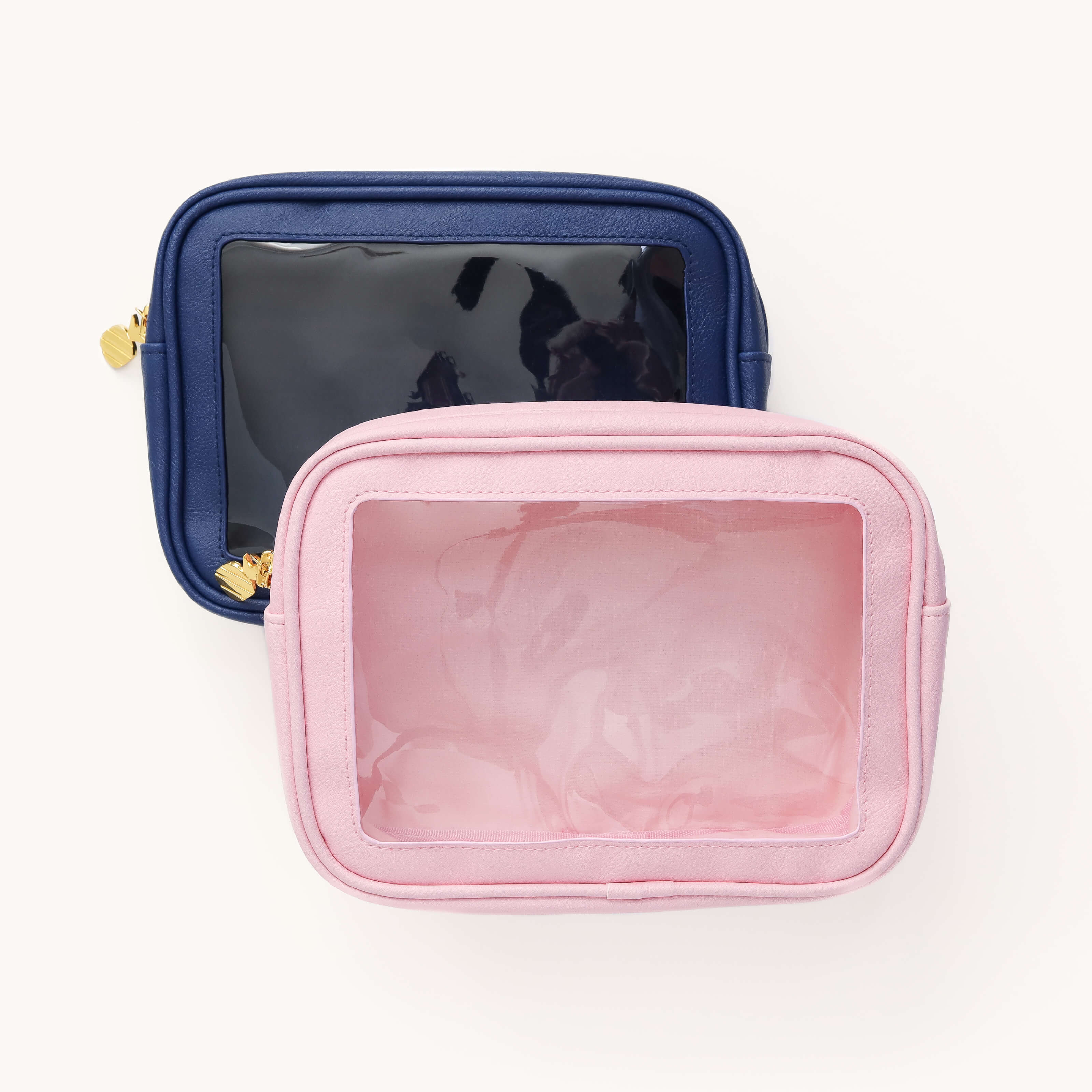 The Simplified Leatherette Travel Bags Bundle includes two stylish TSA-friendly bags with transparent fronts: a dark blue top bag and a pink bottom one, each adorned with elegant gold zippers, perfect for organized travel. Save on this chic pair from Simplified!