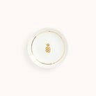 The Trinket Dish - Ceramic by Simplified features a white saucer design with a gold pineapple at its center, accented by a gold rim and set against a light gray background, ideal for use as a decorative item.