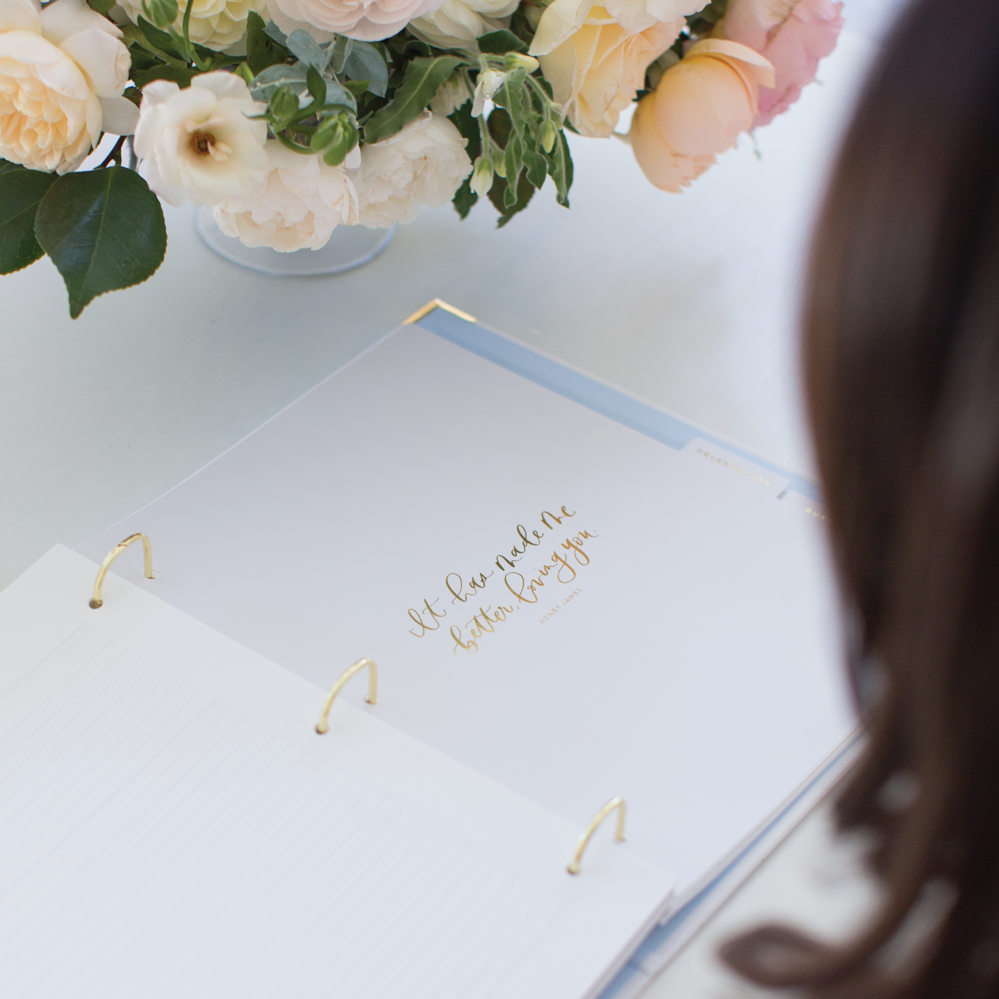 Simplified Wedding Planner by Emily Ley open to a beautifully designed section divider with a gold foil hand-lettered quote. Features elegant gold D-ring binding, a soft blue tab, and premium paper